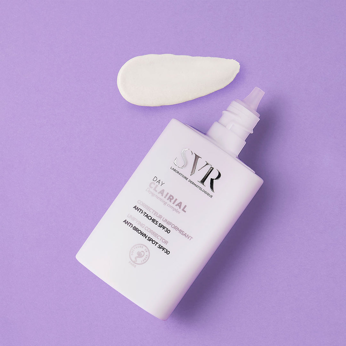 Frasco branco de SVR Clairial Day com doseador e uma amostra de creme sobre fundo roxo.