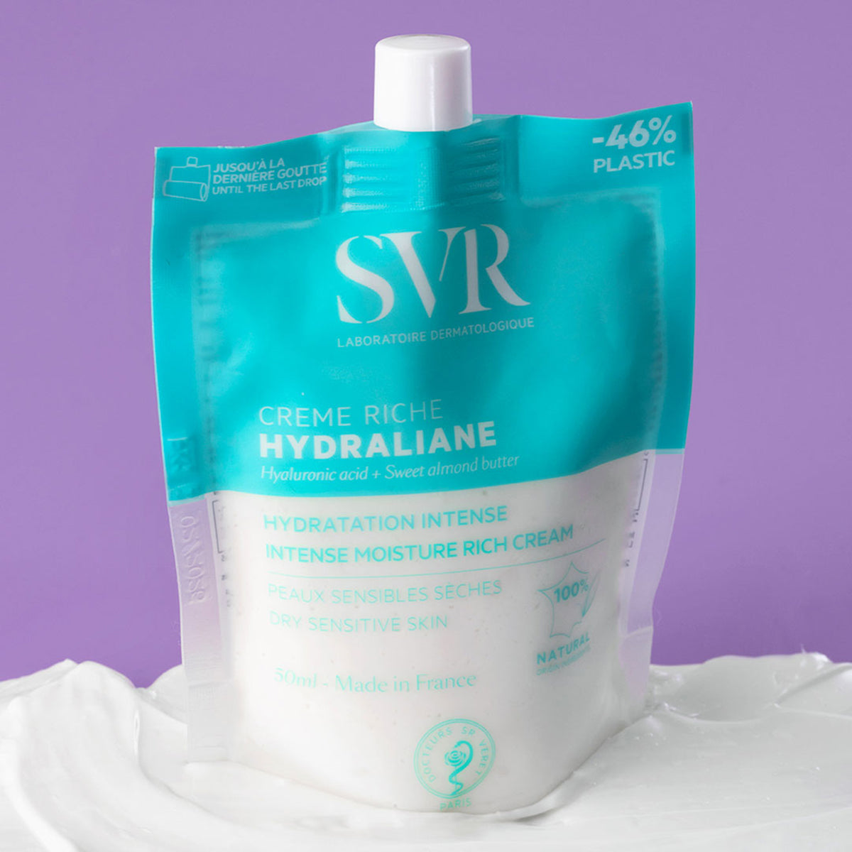Embalagem flexível e sustentável do creme hidratante SVR Hydraliane Creme Riche de 50ml sobre uma textura de creme branco.