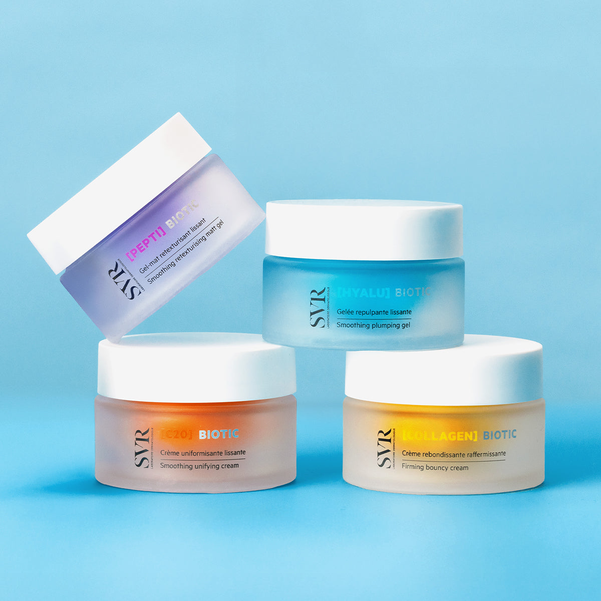 Quatro frascos de creme SVR Biotic com tampas brancas e boiões de vidro fosco em tons de lilás, azul, laranja e amarelo.