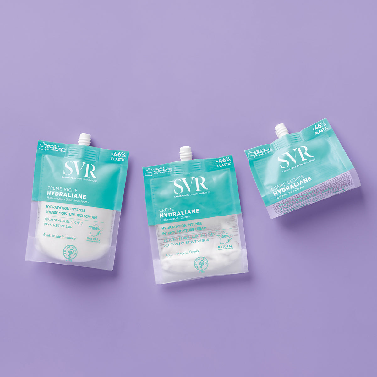 Três embalagens flexíveis de 50ml do creme hidratante SVR Hydraliane em tons de azul-turquesa sobre fundo lilás.