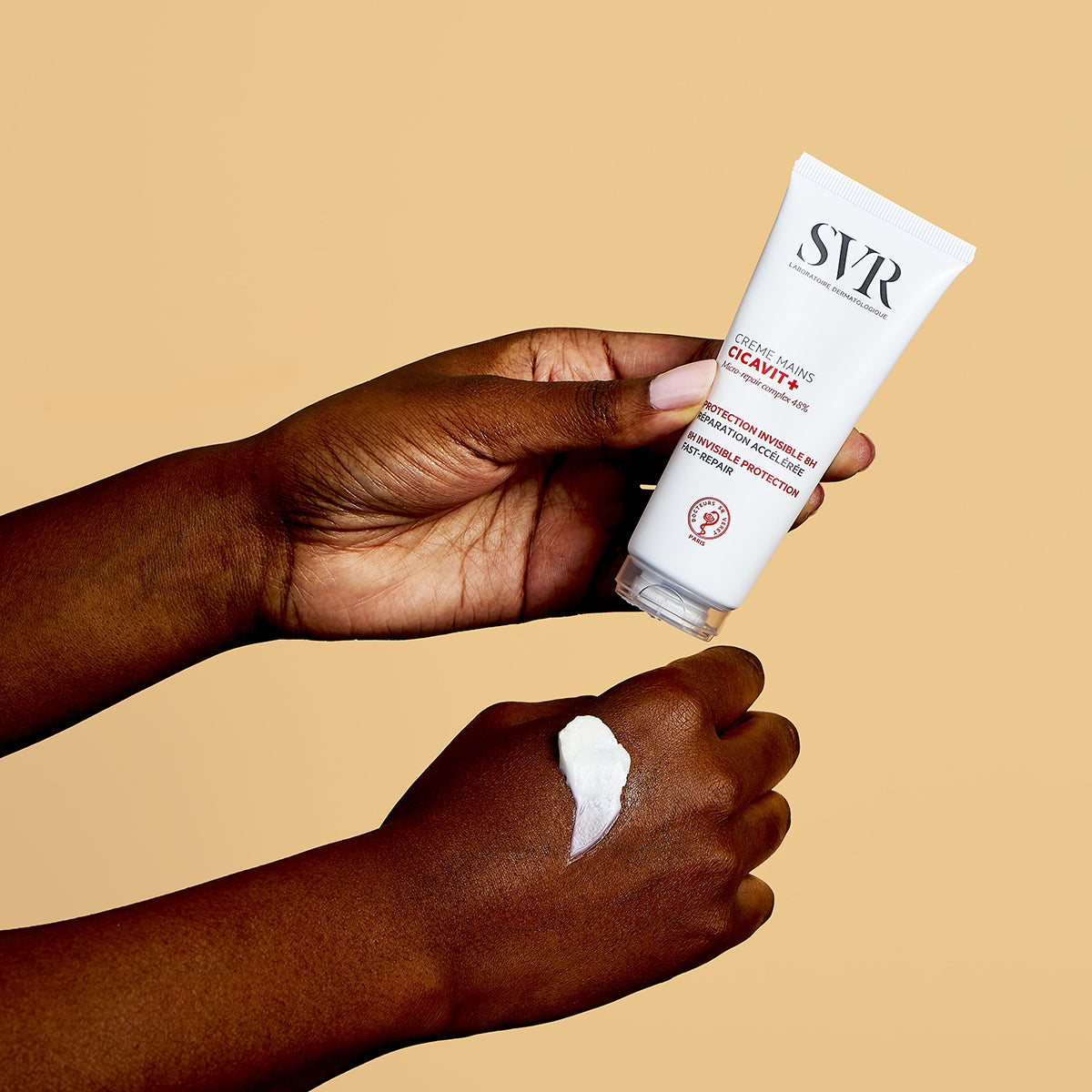 Tubo branco de creme de mãos SVR Cicavit+ sendo aplicado sobre a pele, mostrando a textura cremosa do produto.
