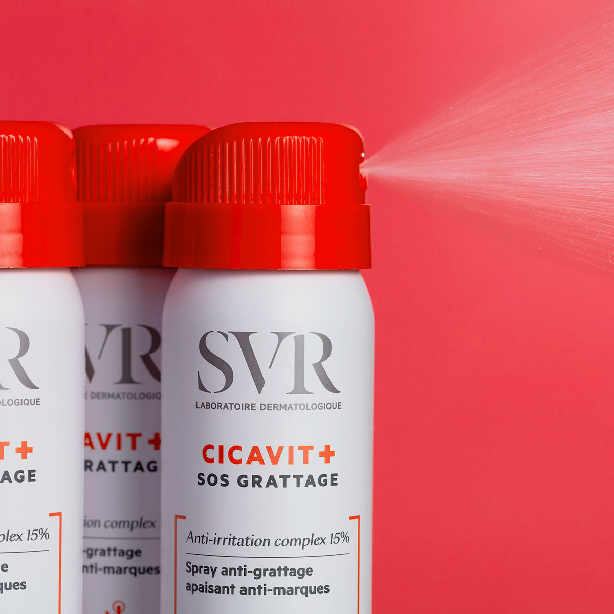 Frasco de spray SVR Cicavit+ SOS Grattage branco com tampa vermelha a pulverizar sobre fundo vermelho vibrante.