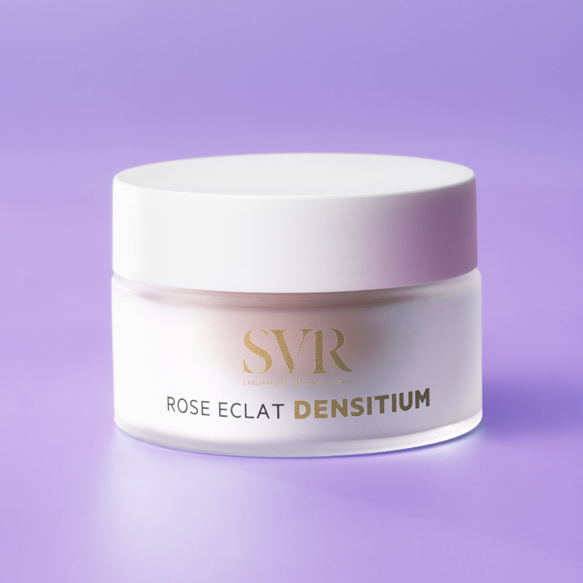 Frasco de creme SVR Densitium Rose Eclat com tampa branca e corpo em vidro fosco sobre fundo lilás.