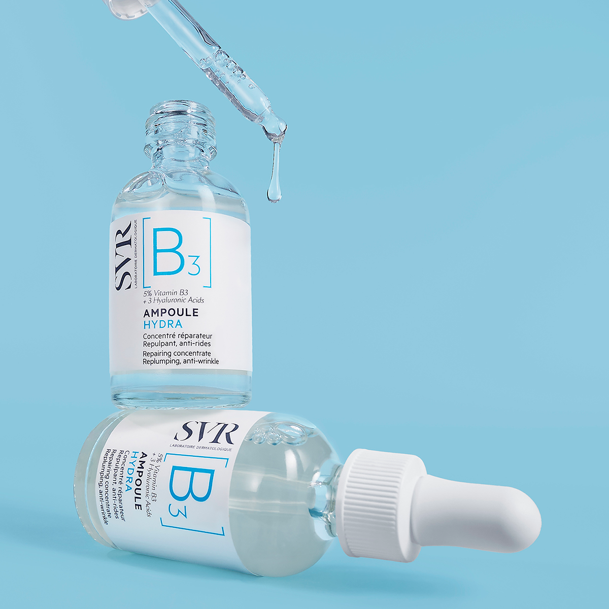 Sérum SVR B3 Ampoule Hydra em frasco de vidro transparente com conta-gotas sobre fundo azul claro.