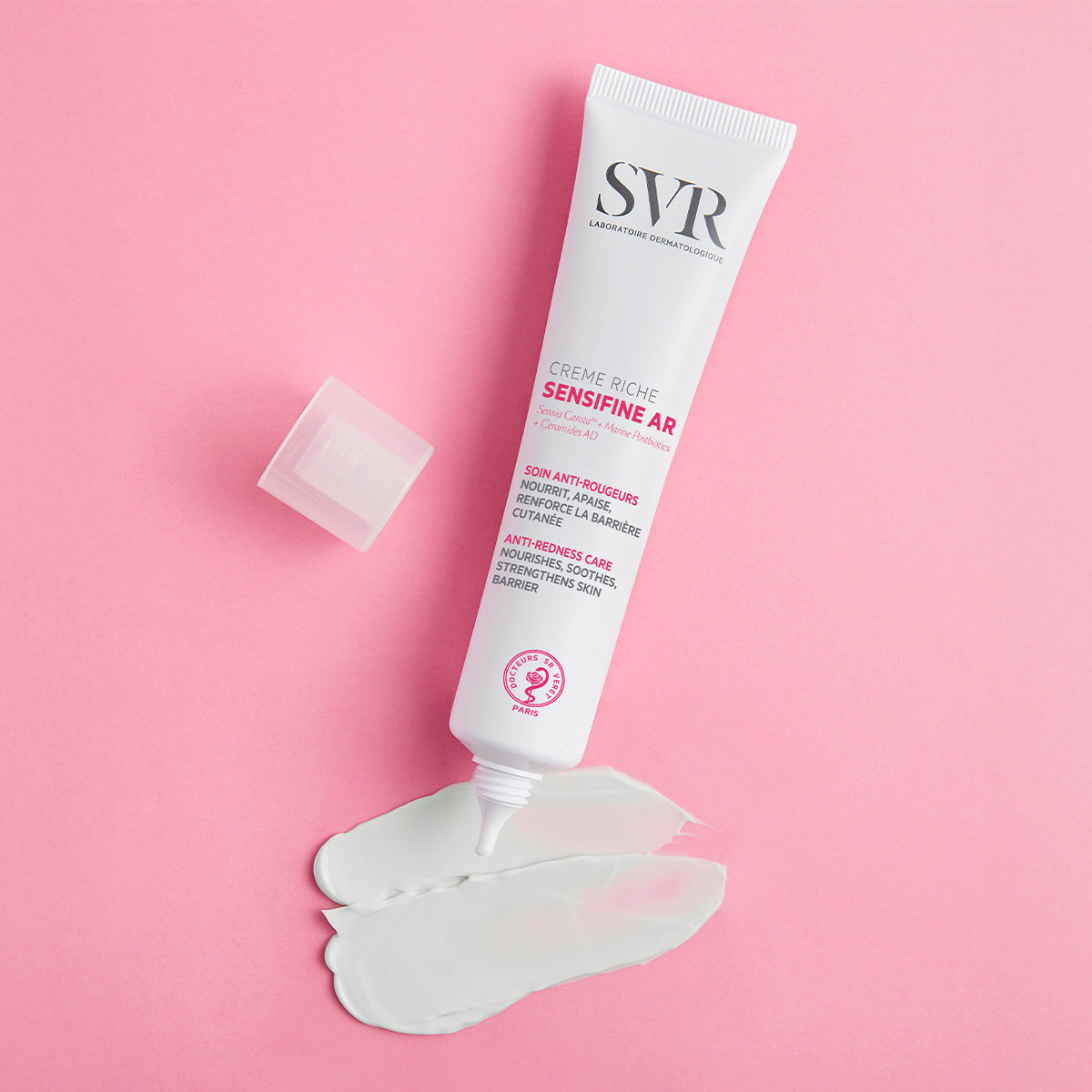 SVR Sensifine AR Creme Riche tube with white cream swatch on a pink background.