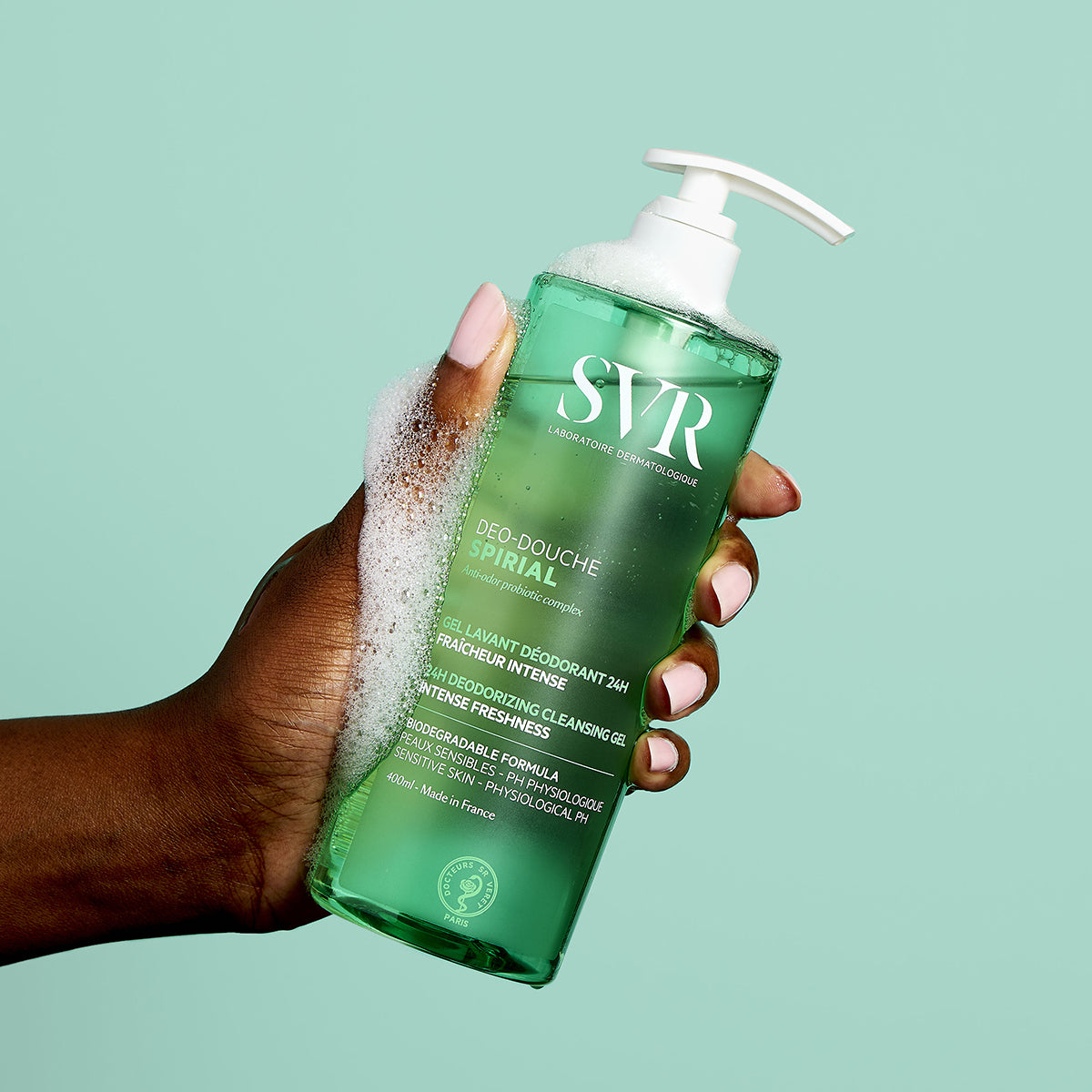 Mão segurando frasco verde de 400ml do gel de duche SVR Spirial Deo-Douche com doseador branco e espuma refrescante.