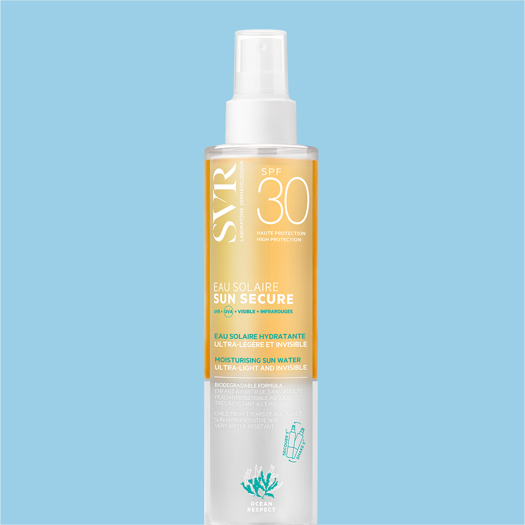 Frasco de spray SVR SUN SECURE Eau Solaire SPF30 com fórmula bifásica transparente e laranja sobre fundo azul claro.