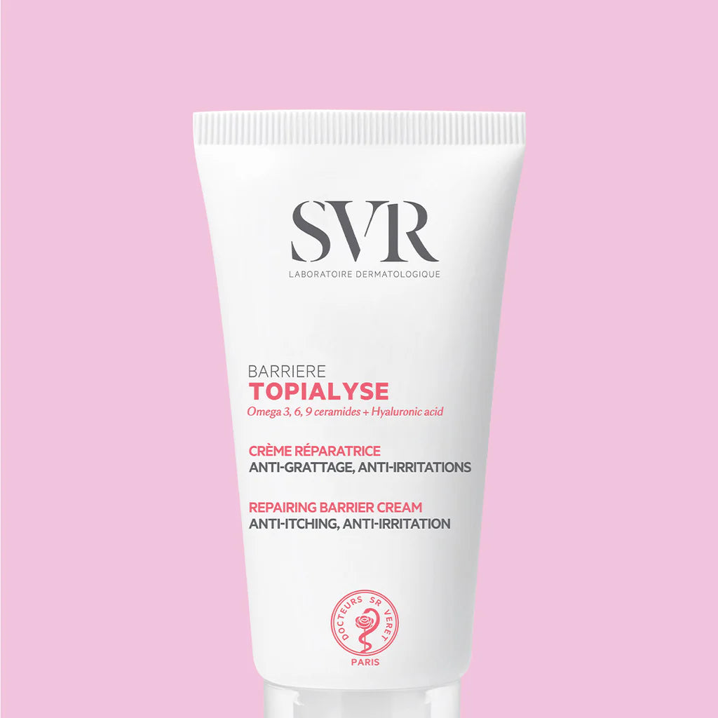 Tubo branco de creme reparador SVR Topialyse Barrière com letras pretas e rosas, isolado sobre um fundo rosa claro.