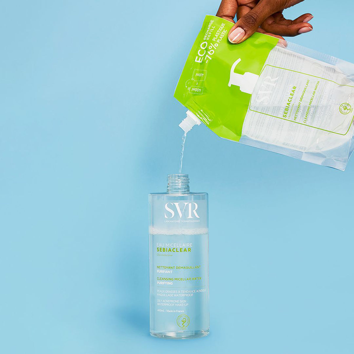 Recarga de 400ml SVR Sebiaclear Eau Micellaire a ser vertida numa embalagem transparente sobre fundo azul claro.