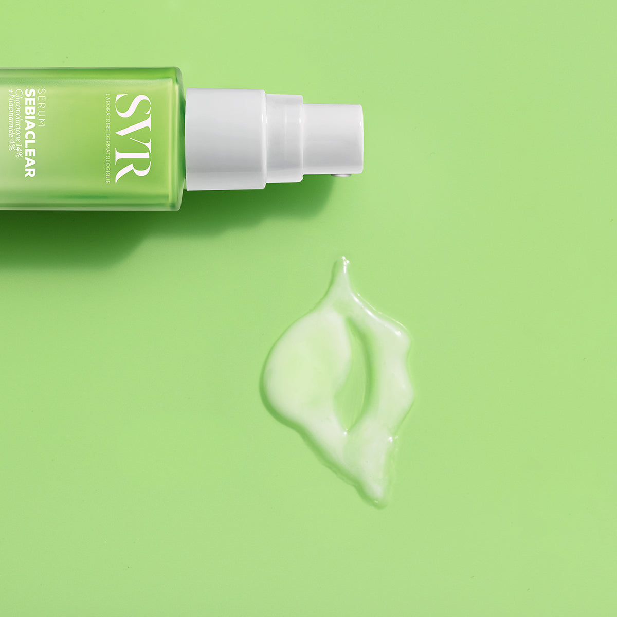 Frasco de SVR Sebiaclear Sérum verde com doseador branco e uma gota de textura fluida sobre fundo verde claro.