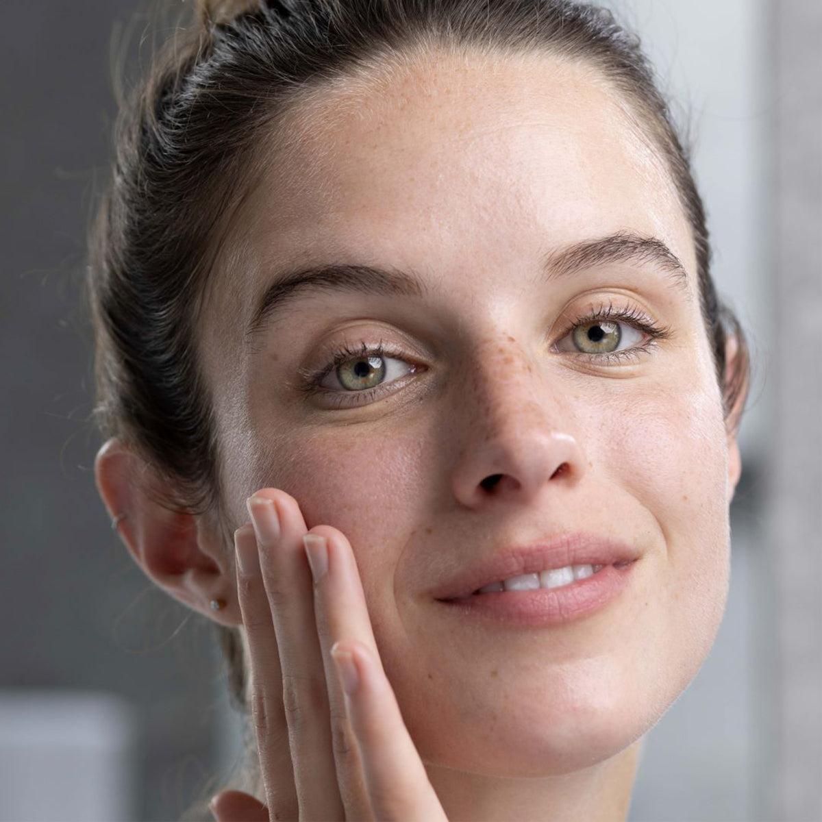 Mulher com pele sensível aplicando suavemente o gel-creme de limpeza SVR Sensifine no rosto com a ponta dos dedos.