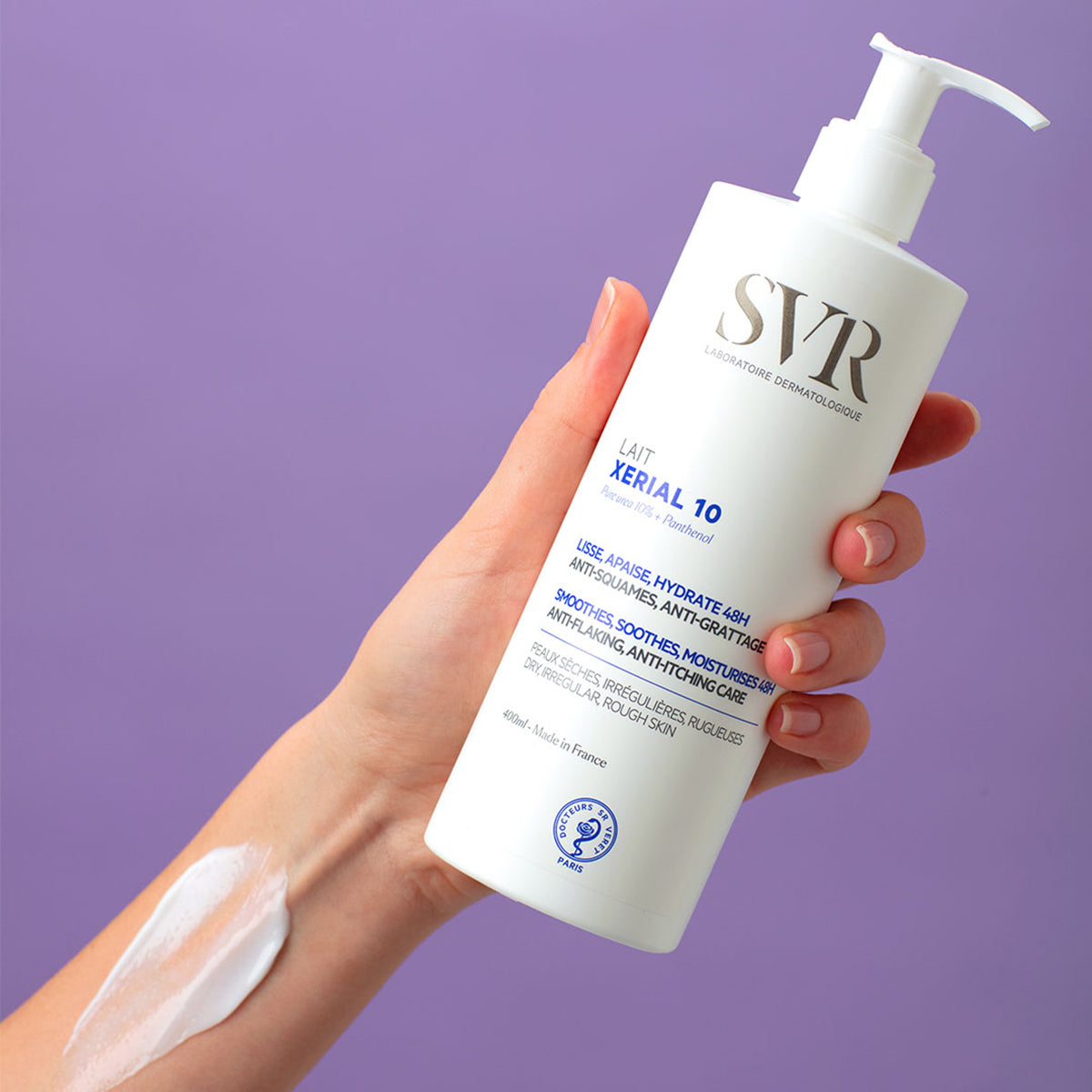 Embalagem branca de 400ml do hidratante SVR Xerial 10 Lait Corps com doseador, segurada por uma mão com creme aplicado.