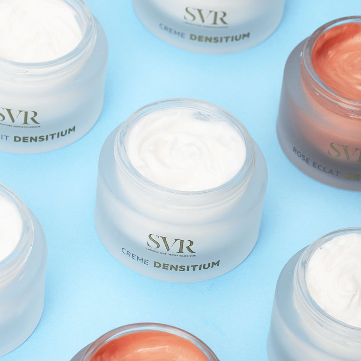 Frascos de creme SVR DENSITIUM com texturas branca e rosada em fundo azul claro.