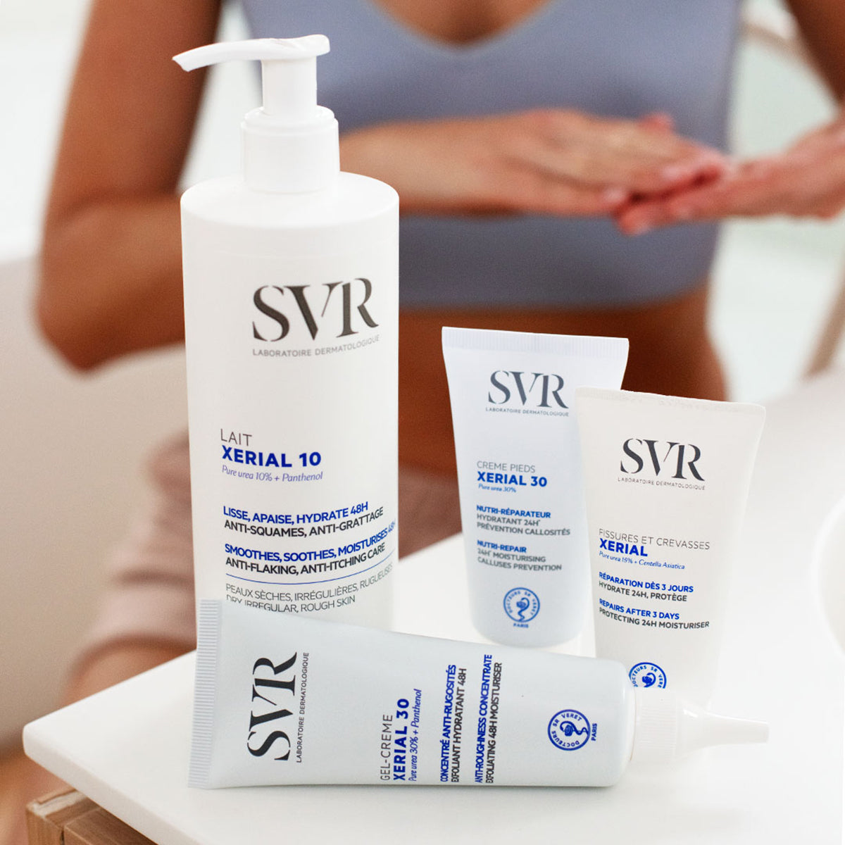 Embalagens brancas de produtos SVR Xerial, incluindo um frasco com doseador e três bisnagas de creme sobre uma mesa branca.