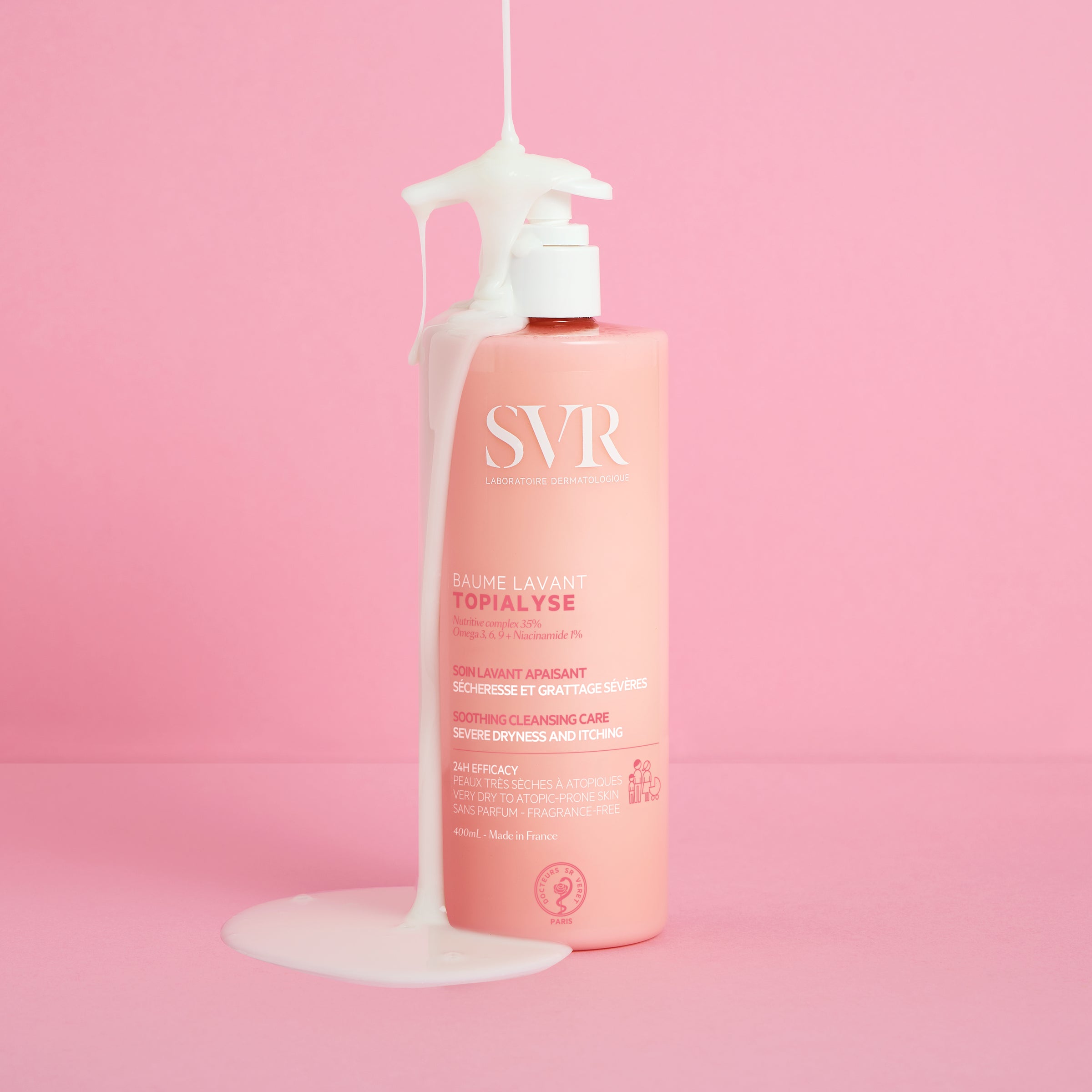 Embalagem rosa de 400ml do bálsamo de limpeza SVR Topialyse com textura cremosa branca a escorrer sobre o frasco.