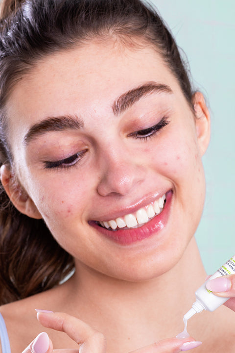 Smiling woman applying SVR Sebiaclear Gel Flash AZ from a small white tube onto her fingertip.